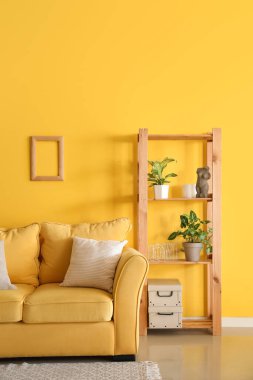Sarı kanepeli ve raf üniteli oturma odasının içi.