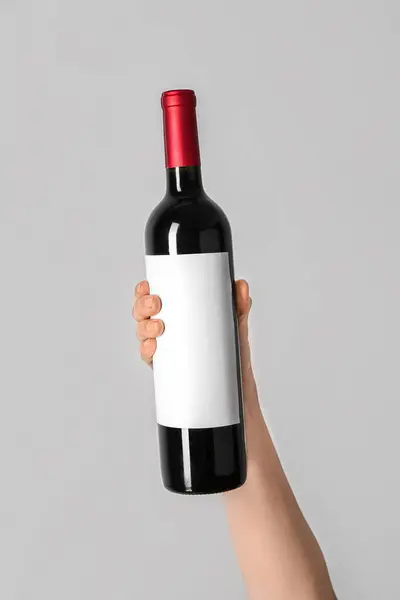 Gri Arka Planda Kırmızı Şarap Şişesini Tutan Kadın — Stok fotoğraf