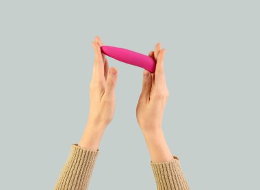 Açık arkaplanda pembe vibratörü olan kadın.