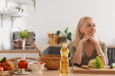 Olgun bir kadın mutfakta sebze salatası yapıyor.