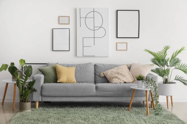 Oturma odasının içinde rahat bir kanepe, resimler ve ev bitkileri var.