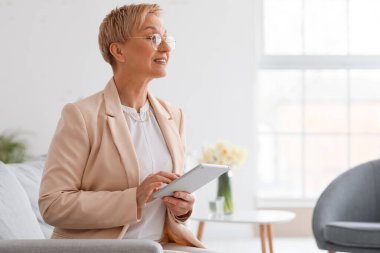 Ofiste tablet bilgisayarla çalışan olgun psikolog.