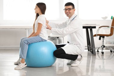 Doktor klinikteki küçük kızın duruşunu kontrol ediyor.