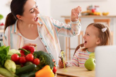 Annesi mutfakta elma soyan küçük bir kız.