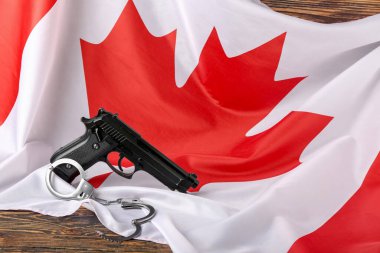 Ahşap arka planda silahlı ve kelepçeli Kanada bayrağı