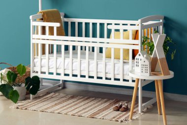 Yatak odasının içinde bebek beşiği ve masa var.