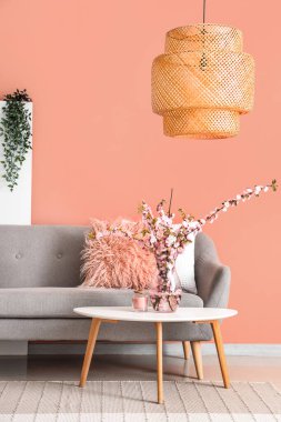 Gri kanepesi ve kahve masasında çiçek açan sakura dalları olan şık bir oturma odası.