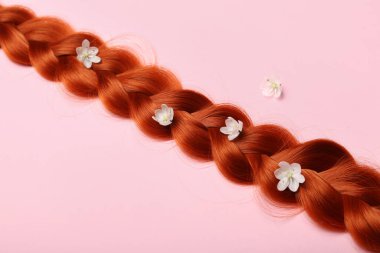 Renkli arka planda çiçeklerle örülmüş kızıl saçlı, yakın plan.