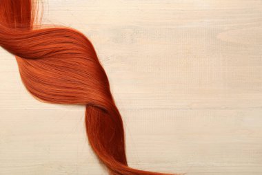 Hafif ahşap arka planda kızıl saç teli, yakın plan.