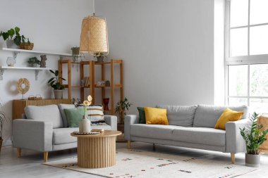 Gri koltukları, ahşap sehpası ve büyük penceresi olan aydınlık oturma odasının içinde.