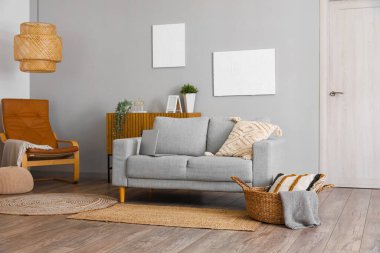 Gri kanepe ve resimlerle aydınlık oturma odasının içinde.