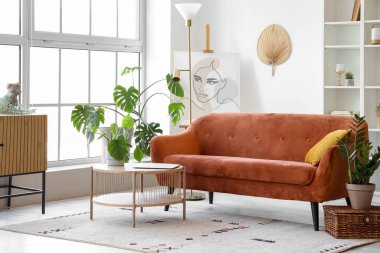 Büyük pencerenin yanında rahat kahverengi kanepe ve sehpası olan bir oturma odası.