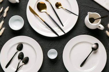 Temiz tabaklar, çatal bıçak takımı ve siyah arkaplanda sürahi ile masa ayarları