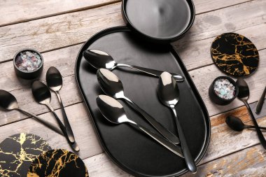 Temiz tabaklar, bir kaşık seti ve aşınmış ahşap masada bardak altlığı.