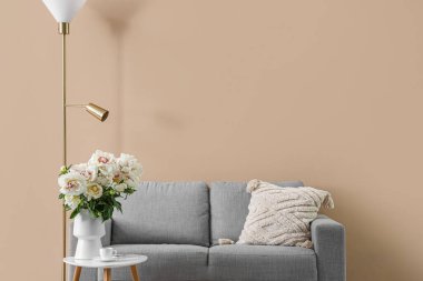 Masalı, kanepeli ve bej duvarlı beyaz şakayık vazosu.