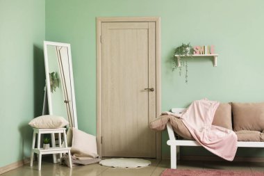 Oturma odası, kanepe, büyük ayna ve kapı.