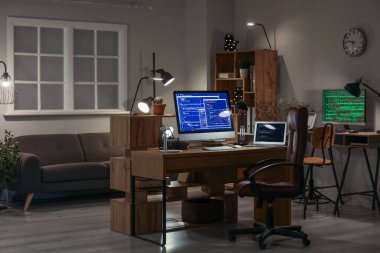 Programcı işyerleriyle birlikte karanlık ofisin içinde.