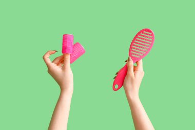 Yeşil arka planda fırçalı ve bigudili kadın elleri