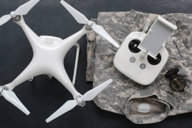 Modern kuadkopter, askeri üniforma, uzaktan kumanda ve siyah arka planda pusula.