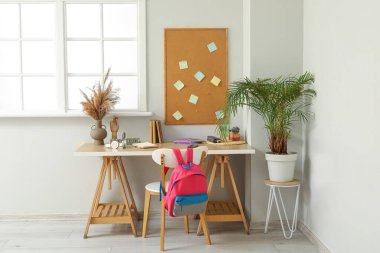 Beyaz duvarın yanında kırtasiye malzemesi olan modern okul masası.