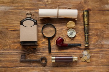 Kahverengi ahşap arka planda bir şişe rom ve farklı korsan ekipmanı.