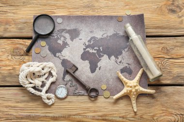 Kahverengi zemin üzerinde kaydırma, büyüteç, bozuk para ve cep saati olan dünya haritası