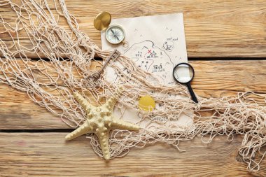 Korsan tılsımlı hazine haritası, büyüteç, pusula ve kahverengi ahşap arka planda ağ