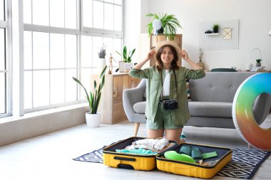 Evdeki bavuldan yaz kıyafetlerini çıkaran genç bir kadın.