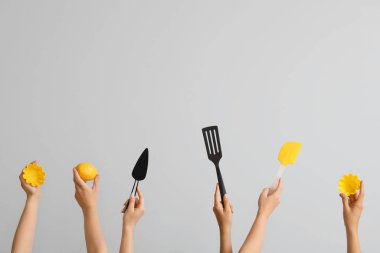 Gri arka planda pişirme aletleri olan kadın elleri