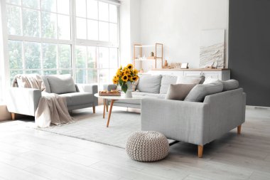 Oturma odasının içinde vazoda ayçiçekleri ve masada kahvaltı.