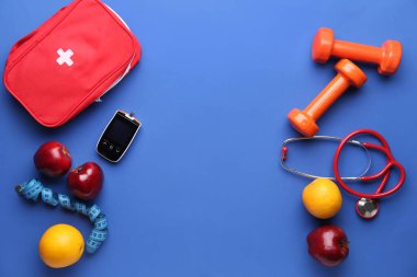 Glukometre, dambıl, meyve, steteskop ve mavi arka planda ilk yardım çantası. Diyabet kavramı