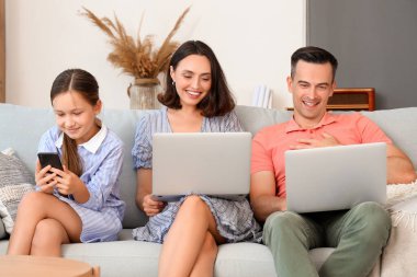 Oturma odasındaki koltukta aletleri olan mutlu bir aile.