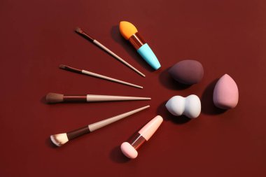 Kırmızı arkaplanda makyaj süngerleri ve fırçalar