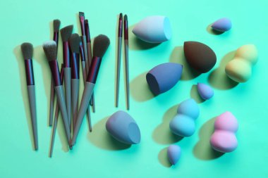 Yeşil arkaplanda makyaj süngerleri ve fırçalar