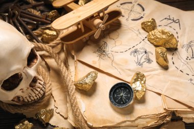 Hazine haritalı insan kafatası, eski el yazmaları ve kahverengi ahşap arka planda altın külçeler.