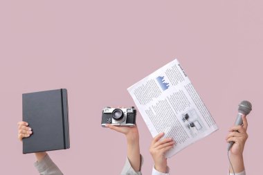Gazete, defter, mikrofon ve fotoğraf makineli kadın eli.