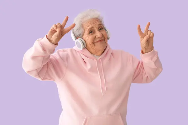 Starsza Kobieta Słuchawkach Tańczy Liliowym Tle — Zdjęcie stockowe