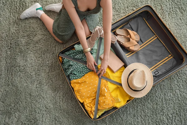 Elbiselerini Bavuldan Çıkarıp Yeşil Halıya Yerleştiren Genç Bir Kadın — Stok fotoğraf
