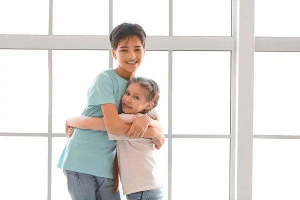 小男孩抱着他靠近窗户的妹妹 — 图库照片