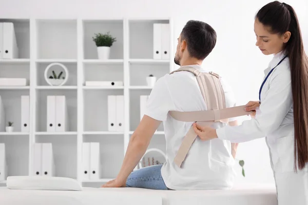 Young man with back brace and female physiotherapist in rehabilitation center
