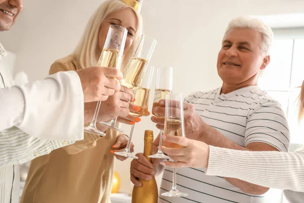 Mature people drinking champagne at Birthday party in kitchen, closeup