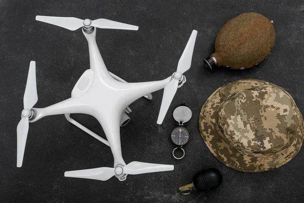 Modern quadcopter, grenade, military hat, flask and compass on black background