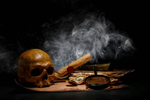 Череп человека со старыми рукописями, туристическое оборудование и карта мира на черном фоне