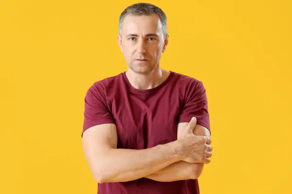 Portrait of mature man with crossed arms on orange background