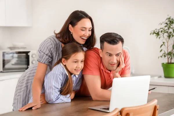 Happy family with laptop resting at table in kitchen