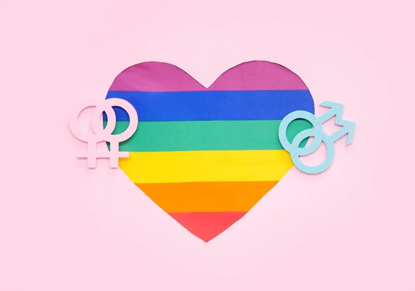 Rainbow heart with male and female gender symbols on pink background. LGBT concept
