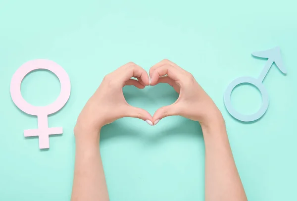 Gender symbols and female hands making heart on turquoise background. Gender equality concept