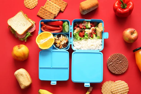 stock image Lunchboxes with different delicious food on red background