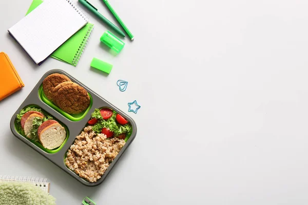 有美味食物和白色背景的不同文具的午餐盒 — 图库照片