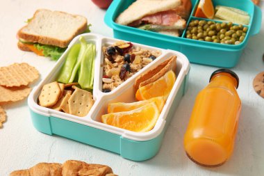 Beslenme çantaları, lezzetli yemekler ve arka planda bir şişe meyve suyu.